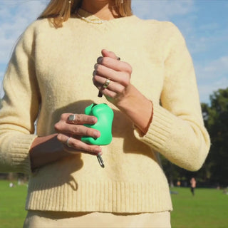 Woman in yellow sweater clipping a green Springer treat dispenser in a sunny park
