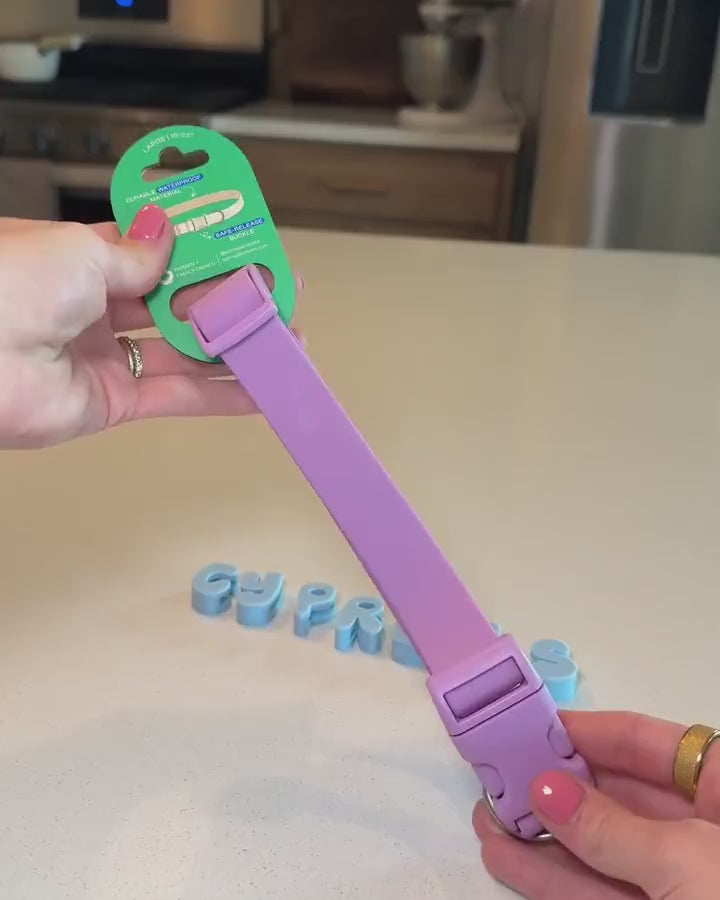 Hand stretching letter charms over the buckle and sliding them onto a lilac collar